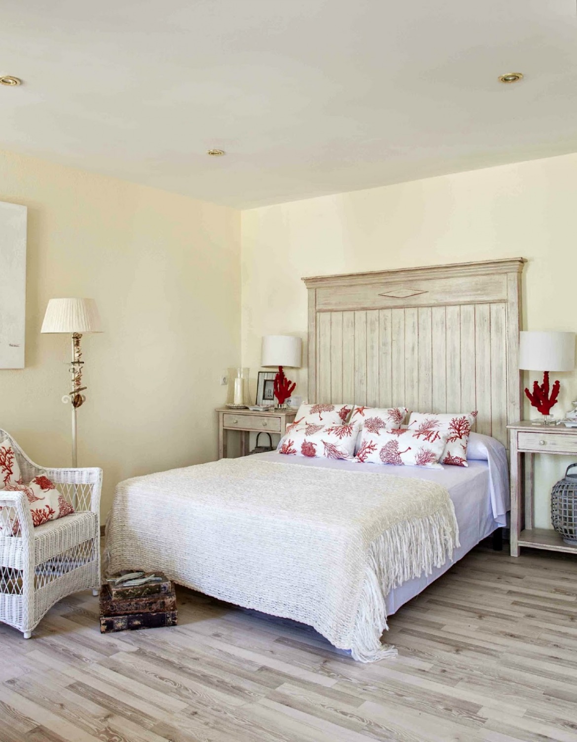 Drewniane bielone łóżko,biały wiklinowy fotel i parkiet w stylu vintage w sypialni z lampkami z czerwonego koralowca (25014)