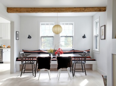 Biała jadalnia z drewnianymi belkami,murowanymi siedziskami z poduchami i różnymi krzesłami przy prostokątnym stole (27011)