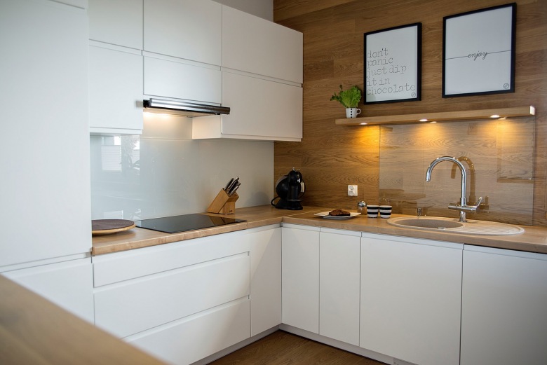 Białe szafki w kuchni w połączeniu z ciepłym drewnem wyznaczają skandynawski styl aranżacji. Minimalistyczne podejście...