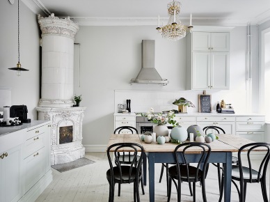 Skandynawska kuchnia z ceramicznym piecem,kryształowym żyrandolem i szarym stołem z postarzanym blatem,krzesła giete z drewna w kuchni (47745)