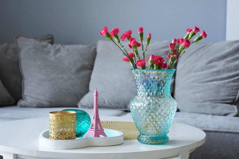 Na stoliku kawowym znajdują się dekoracje w paryskim klimacie. Drobne ozdóbki w różnych kolorach i bukiet kwiatów kreują wyjątkowo przytulny i osobisty...
