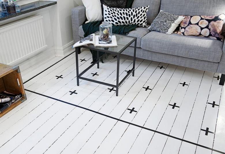 Białe malowane deski z czarnym wzorem szwedzkim zamiast dywanu koło sofy (21208)
