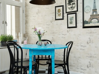 Tapeta ścienna z napisami w stylu vintage,czarna lampa pendant,czarne krzesła z gietego drewna,niebieski okrągły stół i biało-czarna terakota ułożona w szachownicę w kuchni (25860)