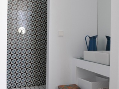 Murowane białe półki w łazience,drewniany ażurowy podest w kabinie,wzorzysta glazura w hiszpańskim stylu,stołek vintage,niebieskie metalowy dzban na wodę w śródziemnomorskiej łazience (26018)