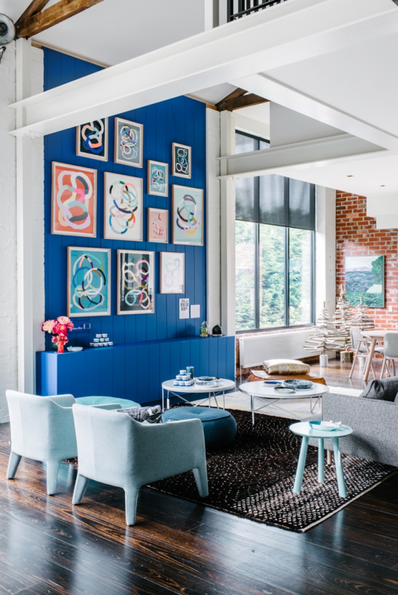 Niebieska ściana, niebieska komoda i błękitne fotele na biało-czarnym dywanie. Cudowne wnętrze, odważne, pełne energii...