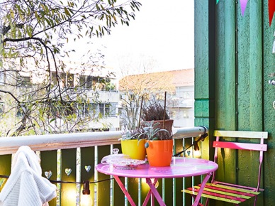 Kolorowa aranżacja małego balkonu z różowym stolikiem i proporczykami (21706)