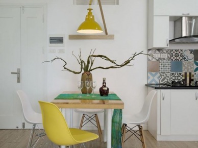 Żółta lampa na drewnianym wysięgniku,żółte krzesło i drewniany stół na białych nogach (25089)