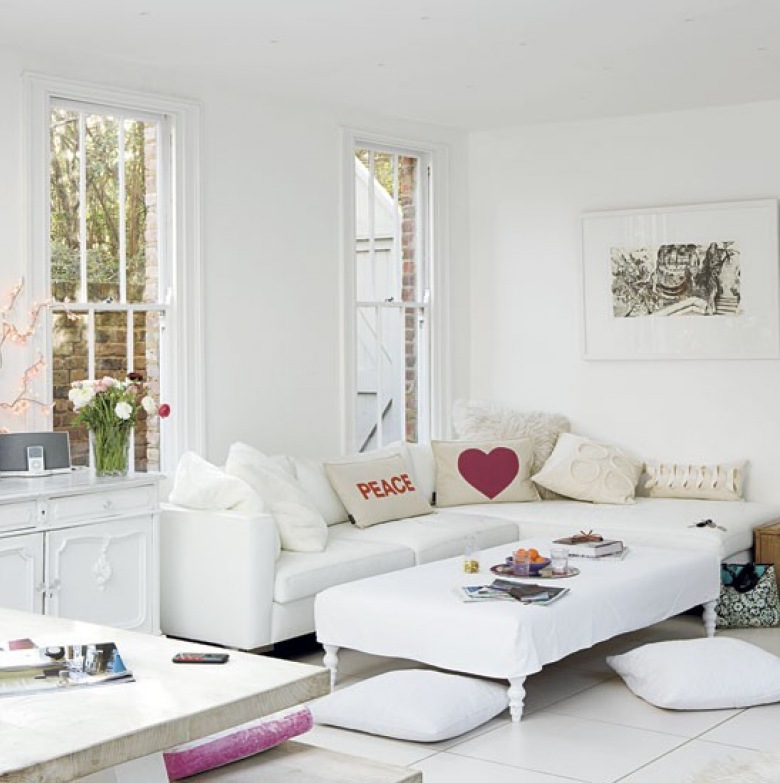 Biały narożnik z poduszkami z różowymi wzorami w aranżacji białego salonu (22603)