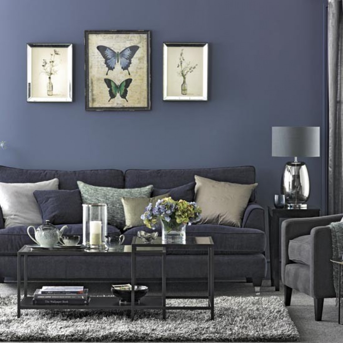 Ciemno-niebieska ściana w salonie z szarą sofą,, metalowymi kwadratowymi stolikami i chromoniklowanymi detalami (26104)
