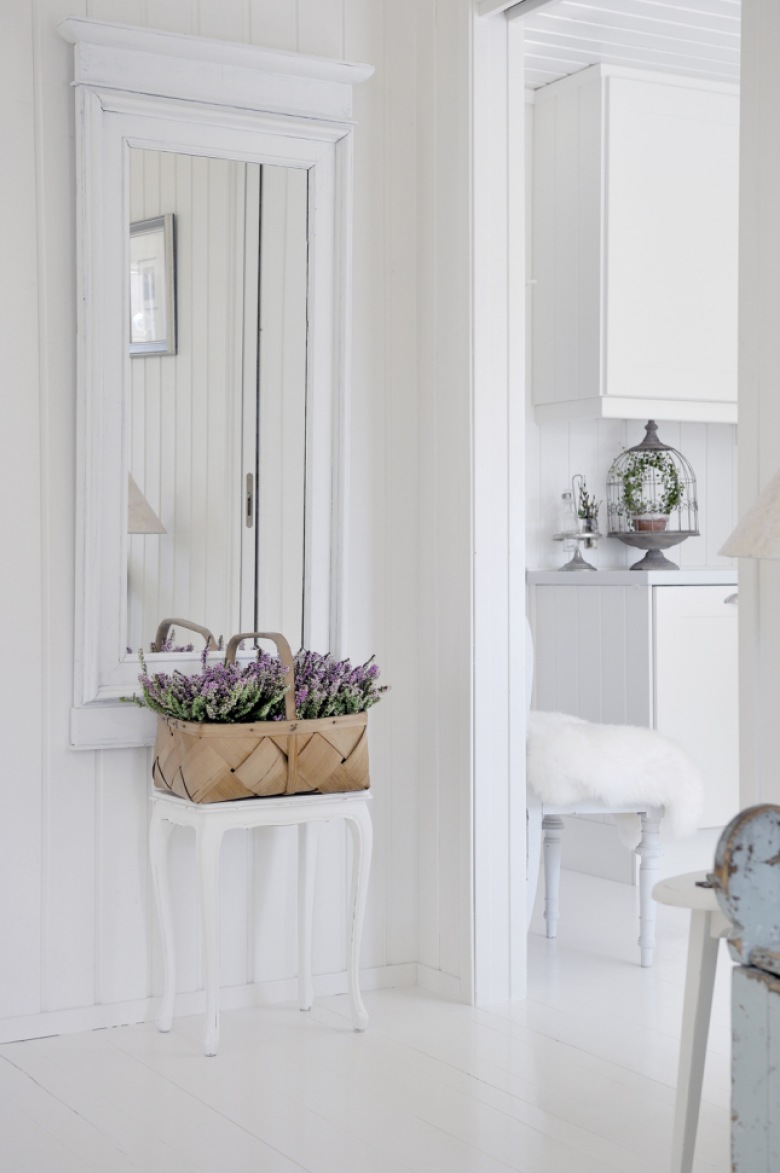 Rustykalne białe lustro z małym styolikiem i plecionym koszem z kwiatami w aranżacji wiejskiego korytarza (24484)