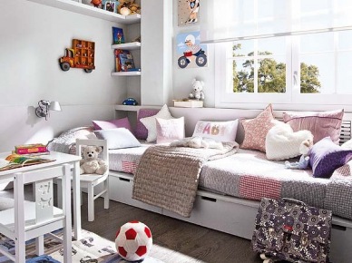 Białe łóżko z szufladami, różowymi i fioletowymi poduszkami w pokoju dziecięcym z półkami i białymi mebelkami (25527)