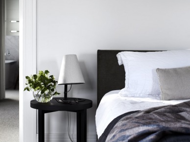 Czarny stolik nocny, pikowane łóżko i biało-szare poduszki i narzuty w sypialni (22939)