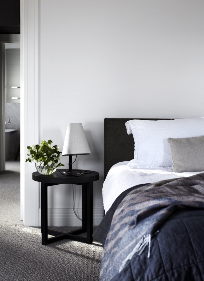 Czarny stolik nocny, pikowane łóżko i biało-szare poduszki i narzuty w sypialni (22939)