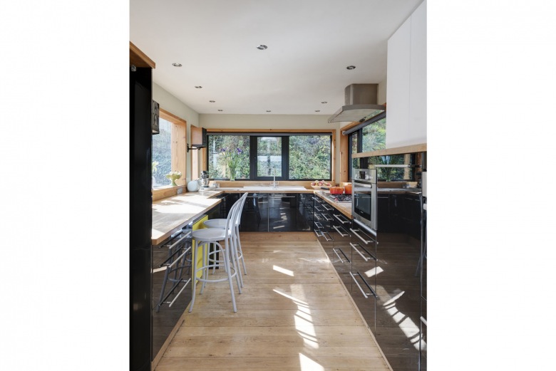 Wystrój kuchni jest dość elegancki i nowoczesny. W aranżacji znajdują się drewniane elementy, w tym podłoga, blaty, a...