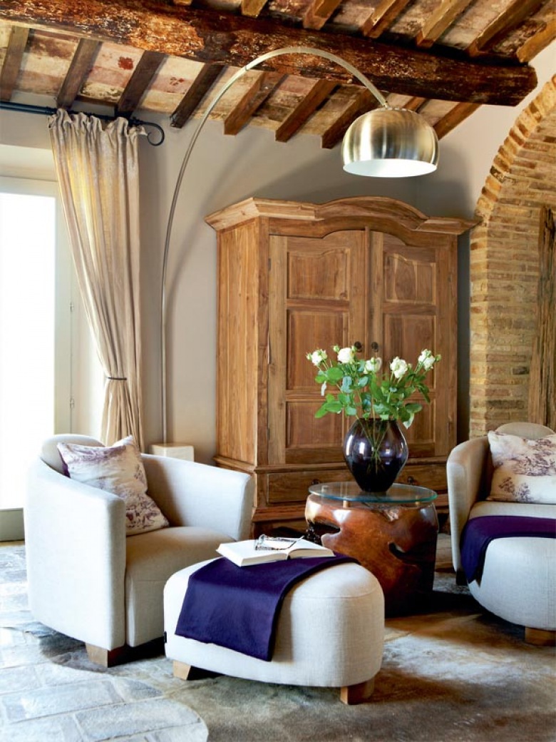 ciepły i swojski klimat w salonie, to drewniane belki, duży, tradycyjny kominek i meble z drewna oraz skórzane sofy - to przykład klasycznego wnętrza we włoskim, wiejskim...