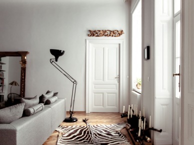 Czarno-biały dywan zebra, nowoczesna biala sofa,industrialna czarna lampa podłogowa i rzexbione stylowe lustro w aranżacji salonu z czarnym sufitem (25578)