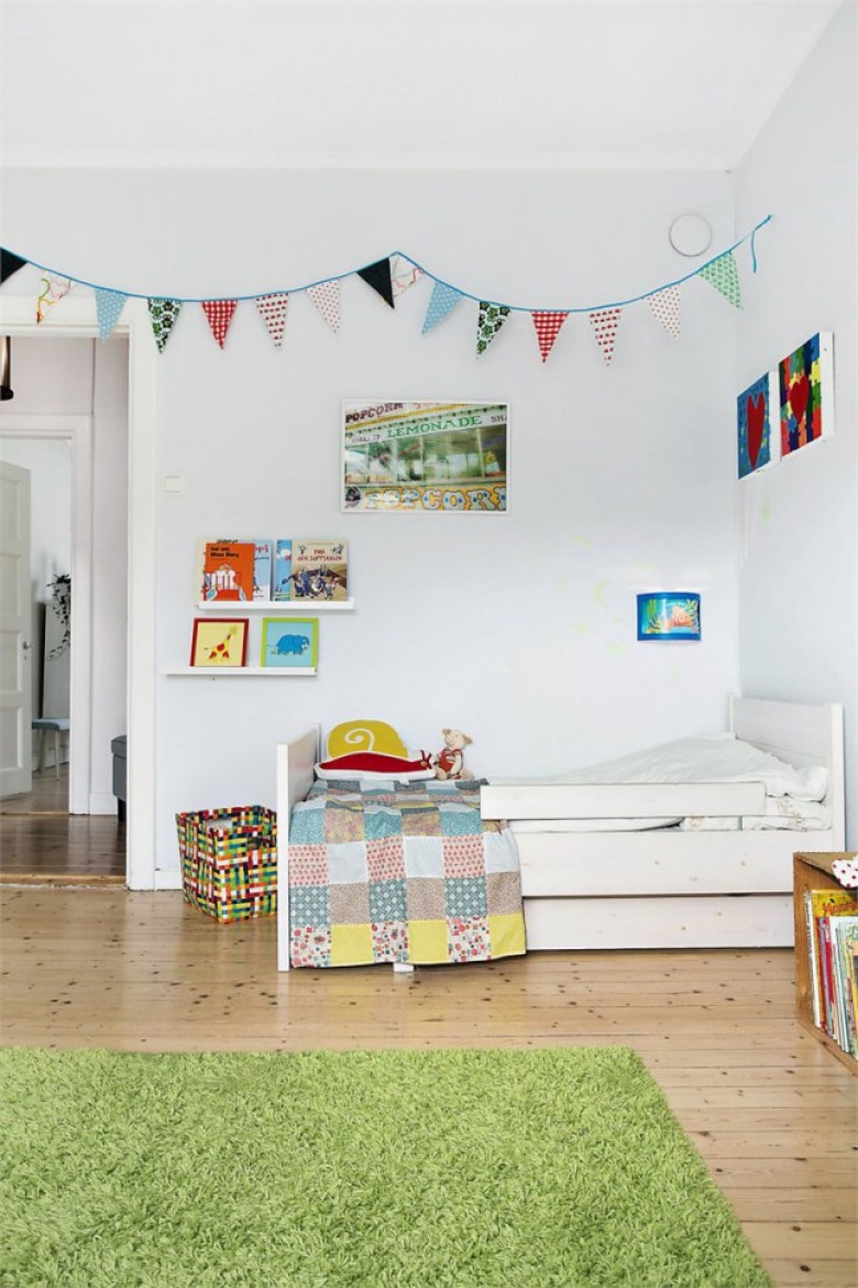 Kolorowa girlanda z proporczykami w dziecięcym pokoju z białymi ścianami i narzutą patchwork na łóżku (25712)