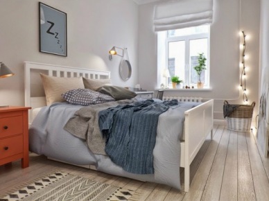 Białe łóżko,skandynawski dywanik z marokańskim wzorem,ruda szafka nocna,szara i niebieska narzuta na łóżku i girlanda z żarówkami w aranżacji sypialni w skandynawskim stylu (26315)
