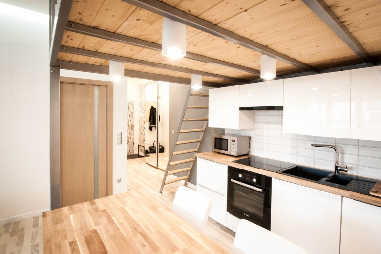 W kuchni białe szafki z lekkim połyskiem idealnie podkreślają nowoczesny charakter całego mieszkania. Jednocześnie...