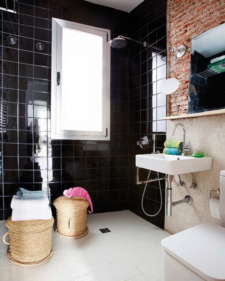 Połączenie czerwonej cegły i czarnych płytek w łazience z dodatkami w kolorze naturalnej wikliny świetnie podkreśla...