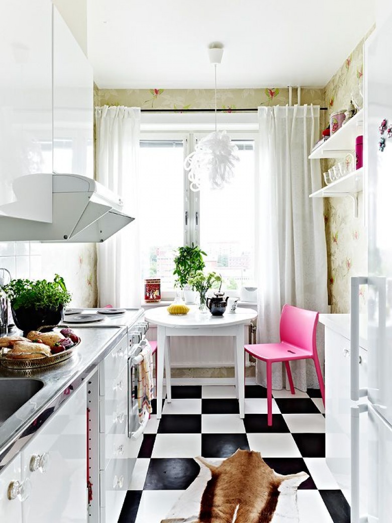 Biała mała kuchnia z różowym krzesłem iczarno-białą posadzką (20438)