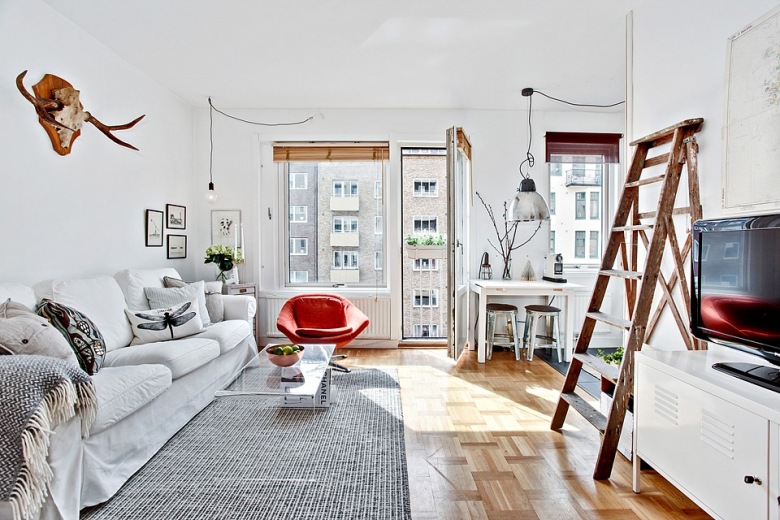 Aranżacja białego salonu skandynawskiego z drabiną,porożem jelonka i czerwonym fotelem (23537)