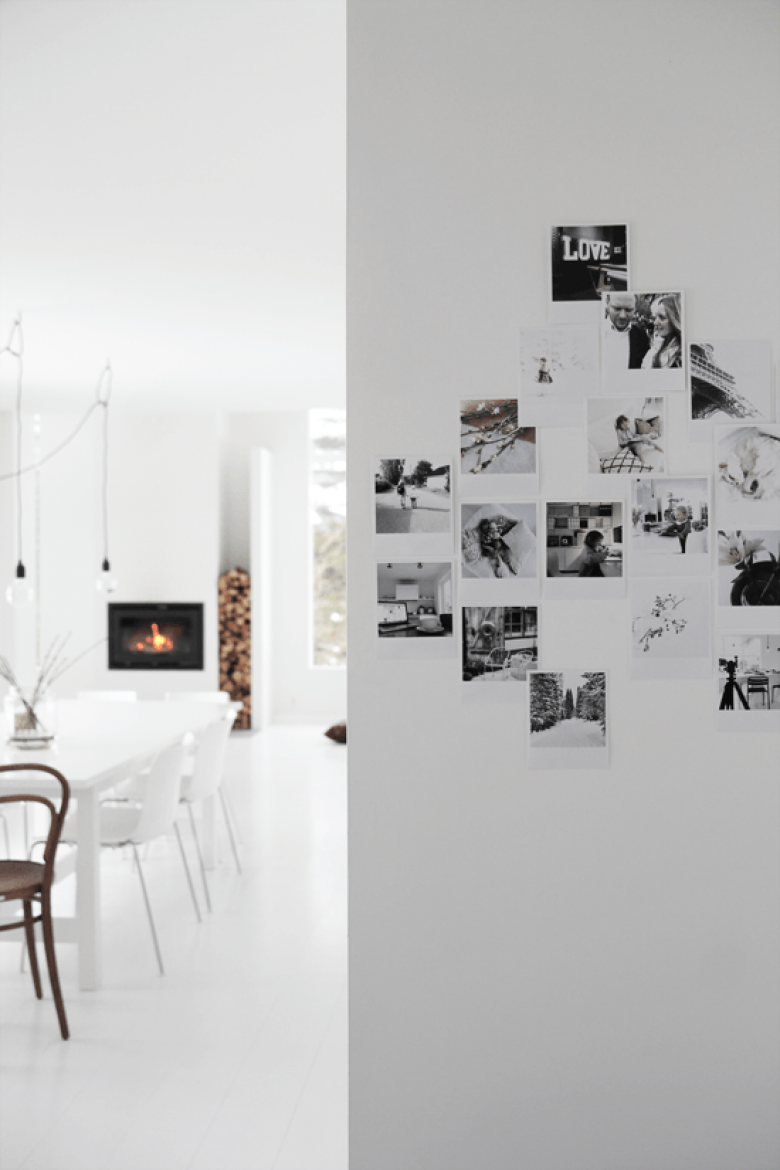 Biały salon z kominkiem i galeria rodzinnych fotografi na ścianie (22650)