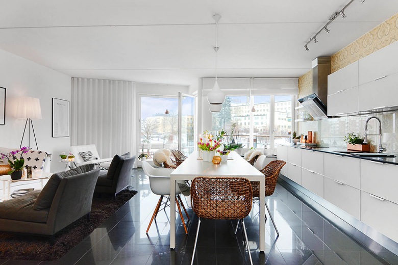 Szare nowoczesne leżanki , biały stół z białymi i miodowymi krzesłami i biała kuchnia w otwartym widoku mieszkania (24641)