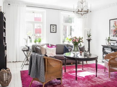 Eklekryczny salon z różowym dywanem i czarnym okrągłym stołem, wiklinowymi fotelami i skandynawskim lampionem (24854)