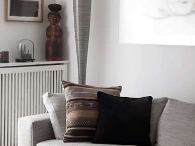 Jasnoszara sofa nowoczesna,brązowo-szara poduszka z etnicznymi wzorami,nowoczesna lampa podłogowa tuba i drewniane posążki (27020)