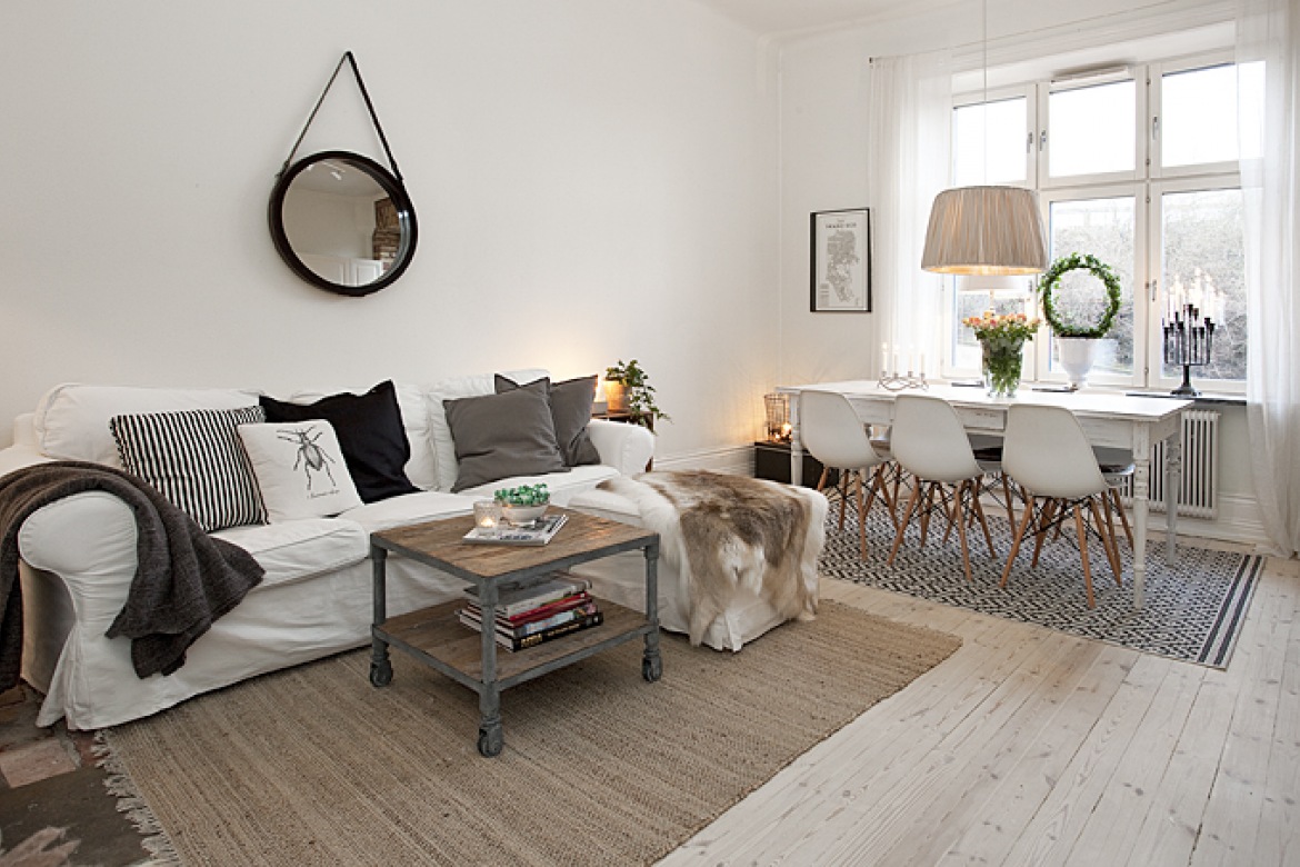 Biała kanapa z poduszkami i skórą w połączeniu z drewnianym stolikiem na kółkach (48846)