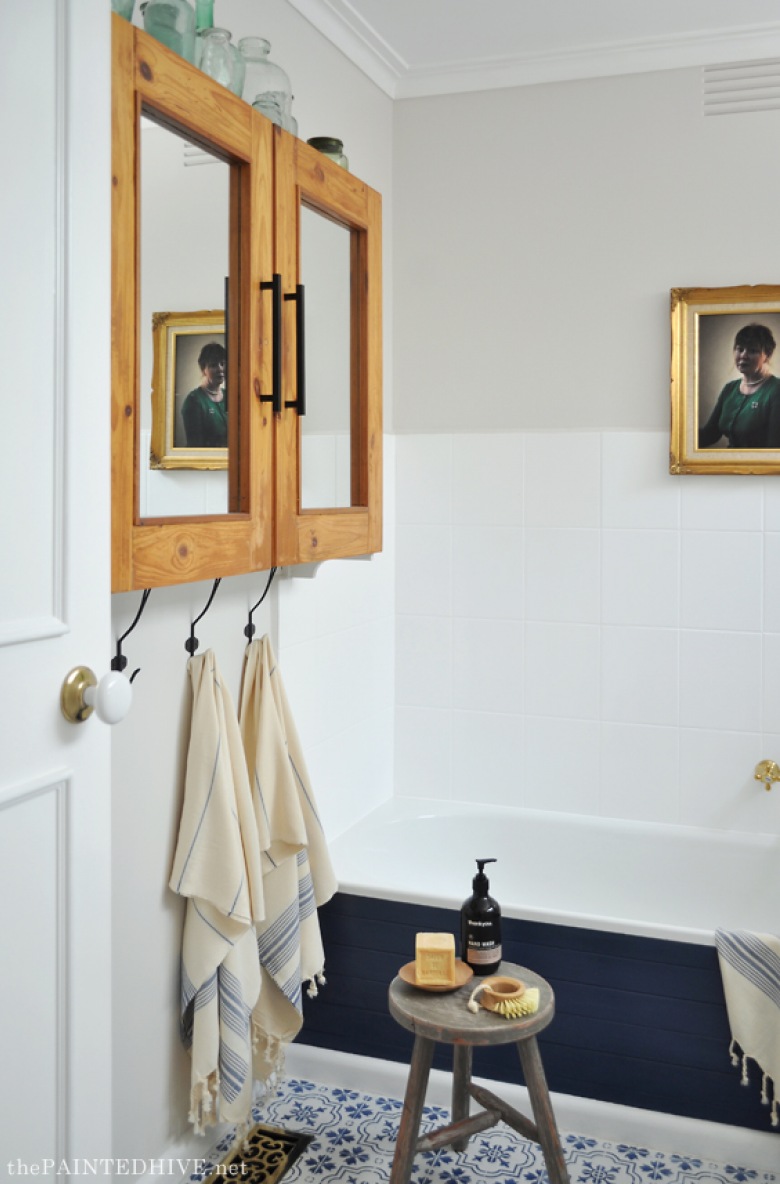Na ścianie w łazience zawieszono piękną szafkę z drewnianymi drzwiczkami i lustrzanym wnętrzem. Każdy detal w aranżacji...
