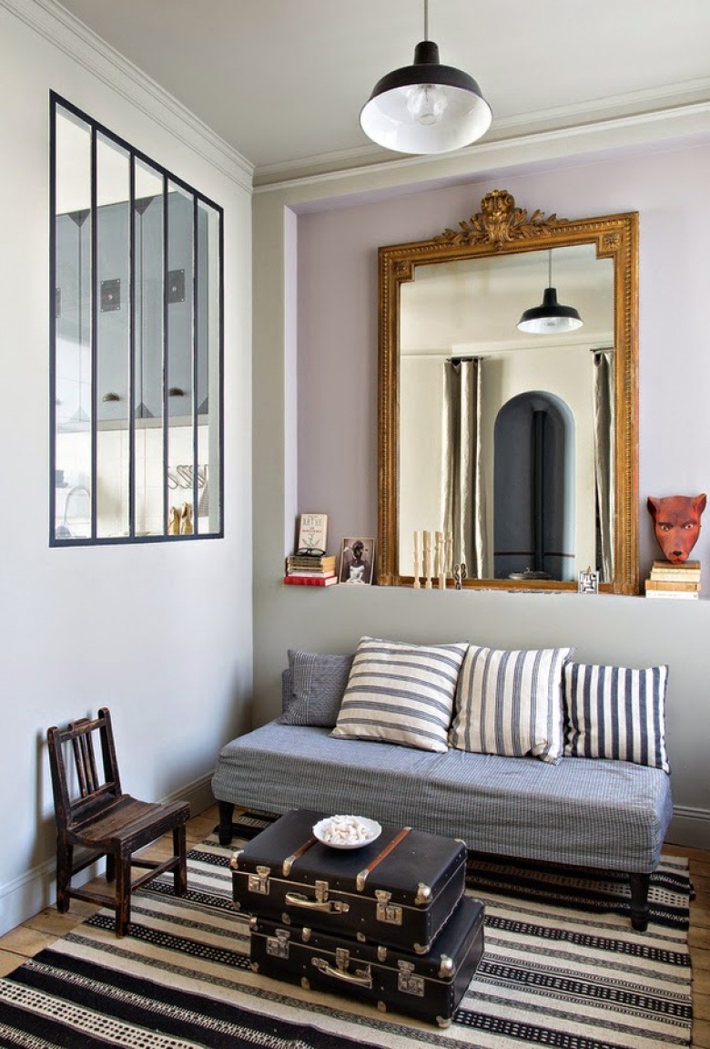 Okno w ściance działowej,stylowe lustro złote,walizki vintage i prosta kanapa poduszlami w niebiesko-biale paski (23665)