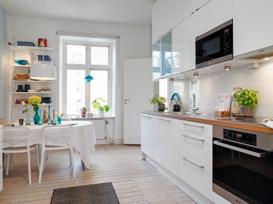Biała nowoczesna kuchnia z drewnianymi blatami,biały stół z krzesłami i białe wiszące półki na ścianie w dekoracji kuchni (25839)