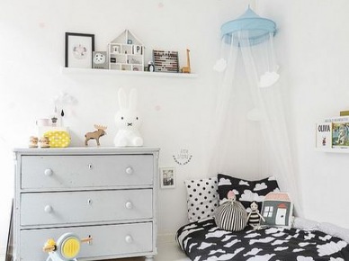 Jasnoszara komoda z szufladami w białym pokoju dziecięcym,biało-czarna pościelk w chmurki i wąska półeczka na ścianie (28504)