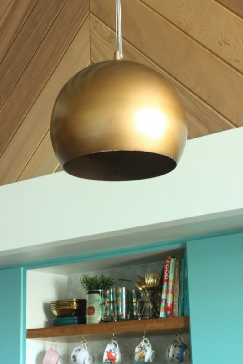 Złote klosze lamp współgrają z innymi złotymi detalami, jakie zastosowano w aranżacji kuchni. Na tle kolorowych szafek...
