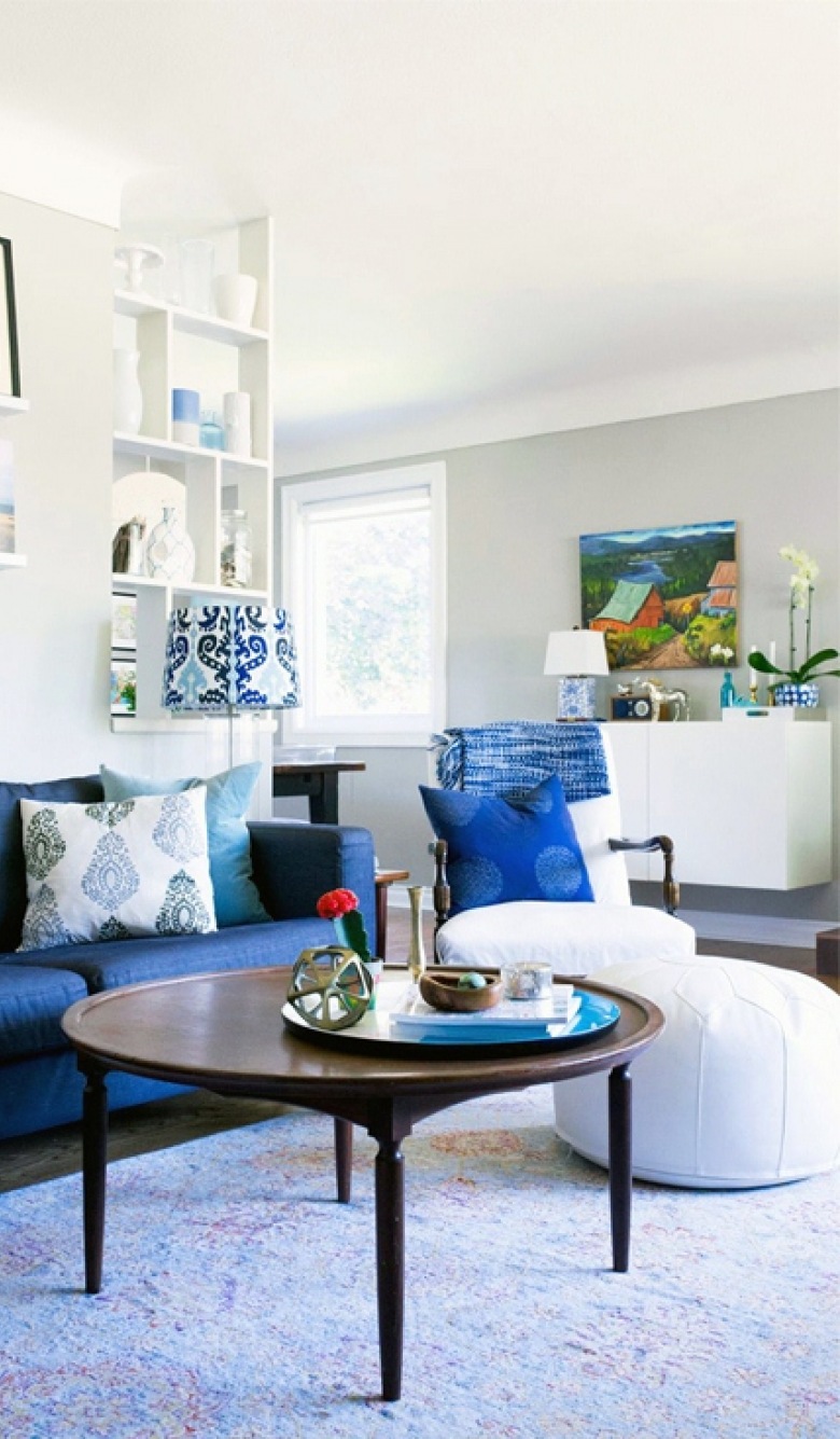 Intensywnie niebieskie obicie sofy w salonie zdecydowanie przyciąga wzrok i tym samym mocno dekoruje przestrzeń. We...