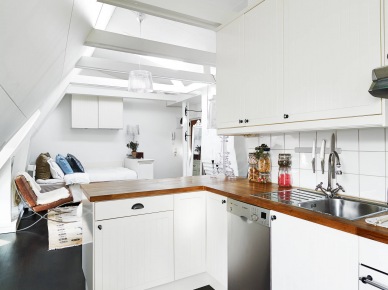 Biała kuchnia z drewnianymi blatami w otwartej zabudowie małego mieszkania (22945)