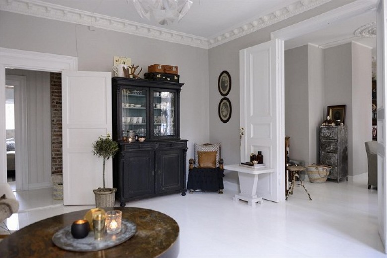 Czarna witryna,stylowy stół i biale sztukaterie w skandynawskim mieszkaniu,biała podłoga i szare ściany,detale i dekoracje w stylu vintage we wnętrzach, (21603)