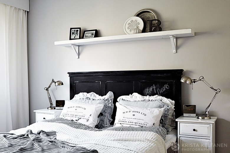 Czarne drewniane wezgłowie łóżka w  białej sypialni,półkanad łóżkiem,metalowe  srebrne lampki nocne,drukowane poduszki na łóżku (48145)