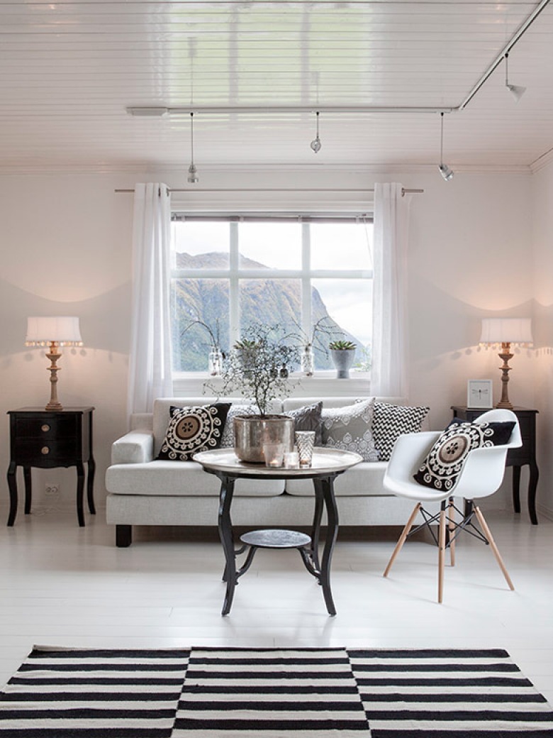 Dywan w biało-czarne paski idealnie pasuje do salony w styku skandynawskim, jest też krzesło eames i czarne szafki.