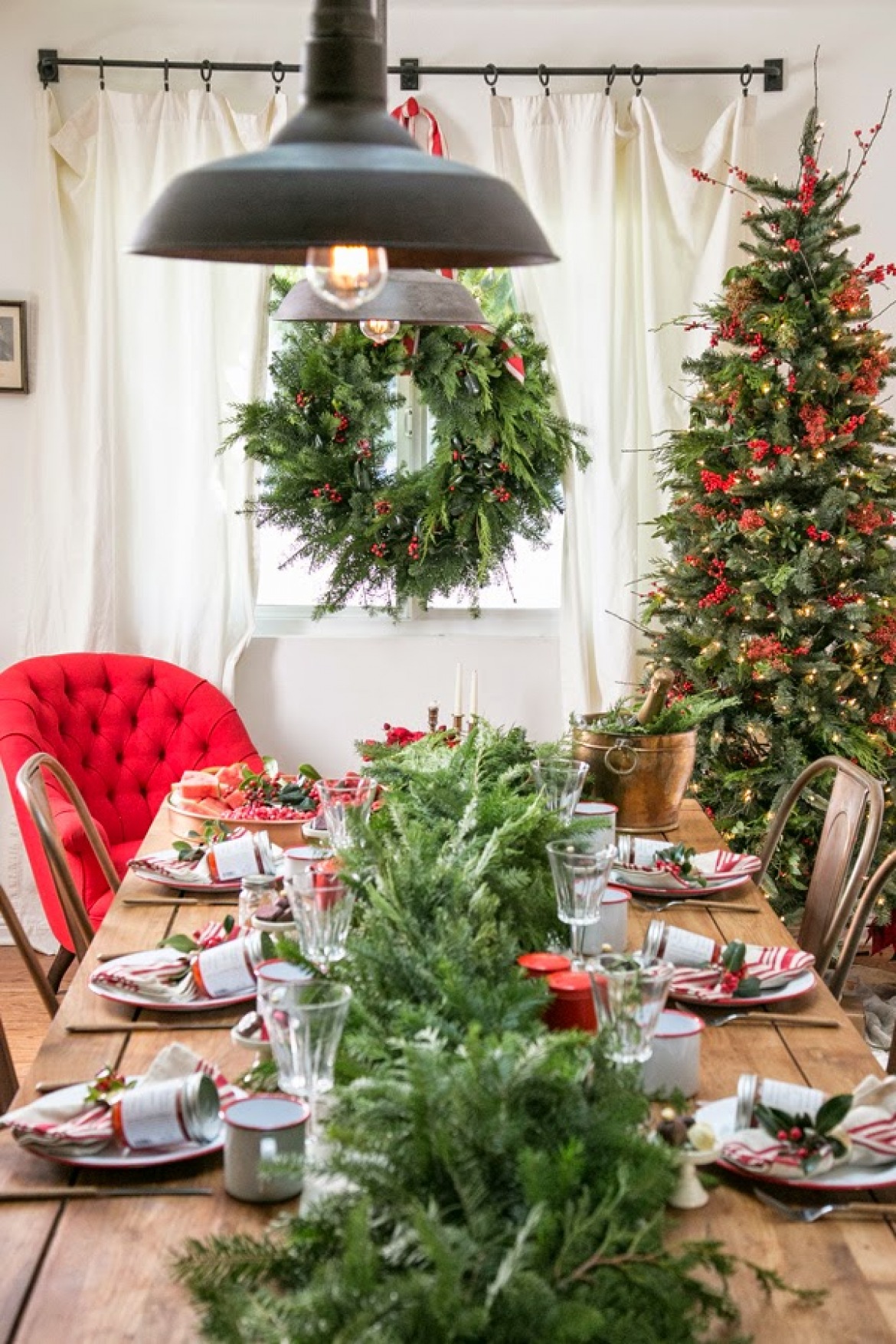 Tradycyjne dekoracje świąteczne stołu z zielonym wiankiem i choinką z czerwonymi dekoracjami i krzesłami tolix (27548)