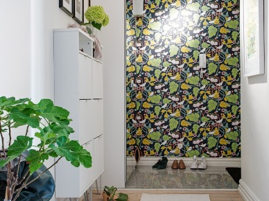 Czarno-zielono-żółta tapeta na ścianie w przedpokoju,biala szafa z lustrzanymi drzwiami i wąska komoda na buty przy białej ścianie (25846)
