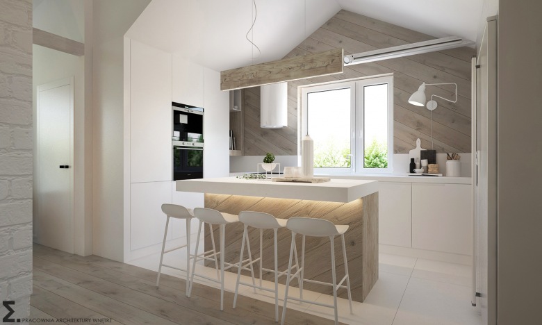 W aranżacji kuchni urzeka połączenie bieli oraz jasnego drewna, szczególnie w postaci desek na ścianie z oknem. Wyspa...