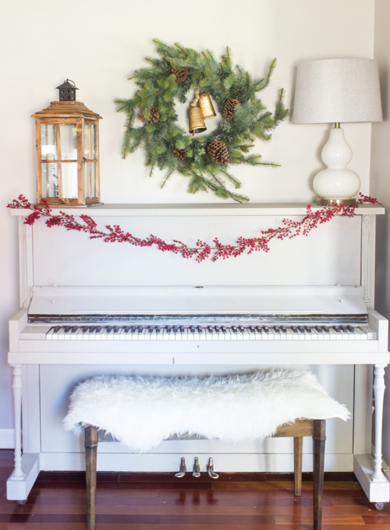 Białe pianino w salonie przystrojono drobnymi elementami. Girlanda z czerwonej jarzębiny pięknie się tu prezentuje....