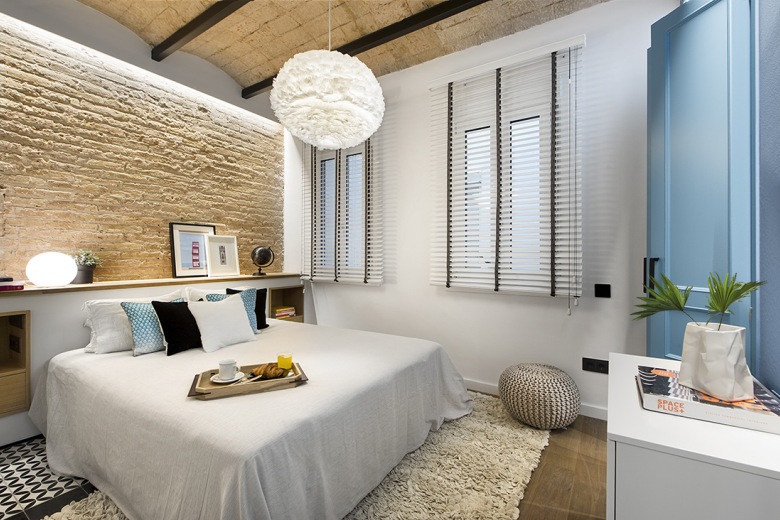 Aranżację sypialni wzbogacają cegły na ścianie oraz drewno połączone czarnymi belkami na suficie. Dzięki temu pokój...