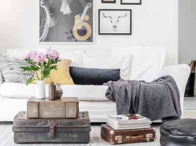 Skórzana i metalowa walizka w stylu vintage,czarna pufa i biała sofa z galerią plakatów na ścianie (24701)