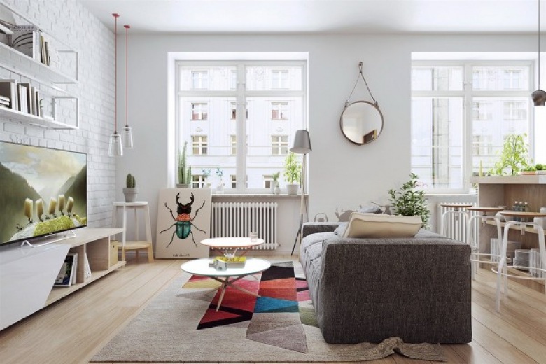 Szara sofa w salonie oraz dominująca biel wyznaczają spokojny styl skandynawski. Przestrzeń znacząco urozmaicają jednak...