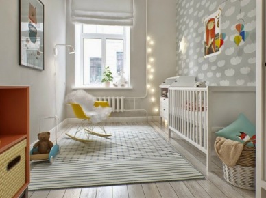 Szara tapeta w chmurki na ścianie w pokoju dla dziecka,fotel na płozach i girlanda z bawełnianymi kulami z żarówkami (26318)