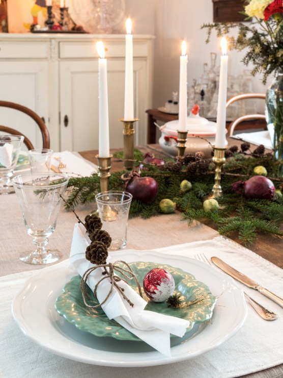 Złote świeczniki i elegancka zastawa stołowa potęgują odświętną aurę, jaka panuje w jadalni. Zielone gałązki świerku...
